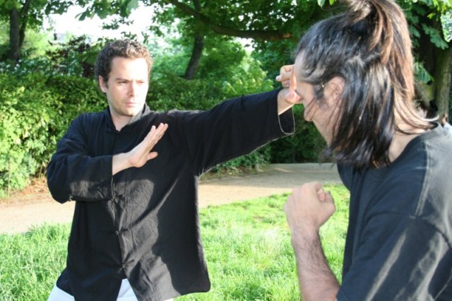 Illustration de Bil Sao (le bras lancé) en wing chun kung fu, ici défense en position côté sur une attaque en crochet, notez le bras tendu et les doigts vers l'intérieur