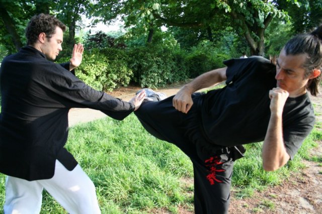 Sur une attaque en coup de pied circulaire, le wing chun kung fu propose à partir de la position "T" une défense en Gum Sao (poussée de la paume vers le bas)